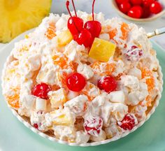 a glass bowl filled with fruit salad on top of a table next to marshmallows