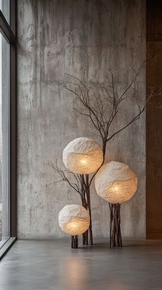 three white lamps sitting next to each other on top of a cement floor in front of a window