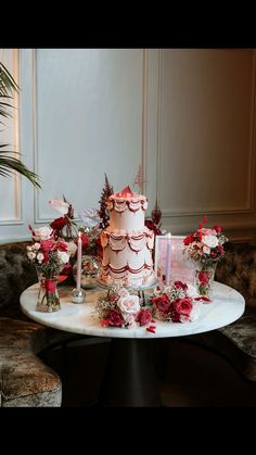 a table topped with a white cake and lots of red flowers on top of it