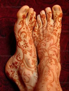 the legs and feet of a woman with henna on her body, showing intricate designs