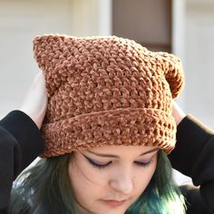 a woman with green hair wearing a brown crochet hat