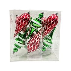 glass christmas ornaments in a clear box on a white background with green and red accents