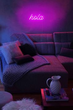 a living room filled with furniture and a neon sign on the wall above it that says holla