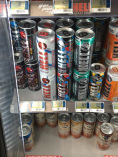 an assortment of cans and cans of energy drinks on display in a grocery store case