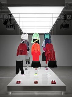 a display case filled with lots of different colored jackets and shoes on top of a white platform