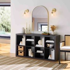 a living room with a mirror, chair and bookshelf on the sideboard