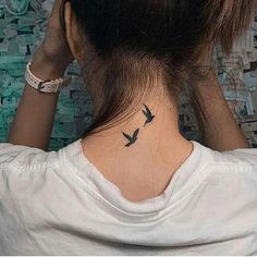 the back of a woman's neck with two birds on her left and right side