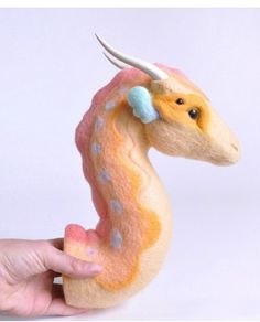 a hand holding a small toy animal with horns on it's head and tail