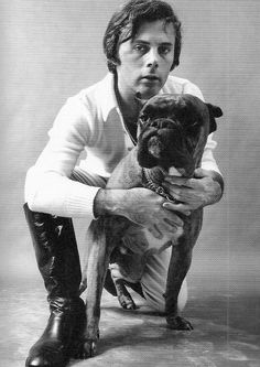 a black and white photo of a man holding a dog in his lap while wearing boots