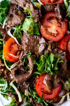 a white plate topped with meat and veggies on top of lettuce