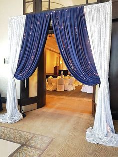 an open door with blue drapes and white table cloths on the floor in front of it