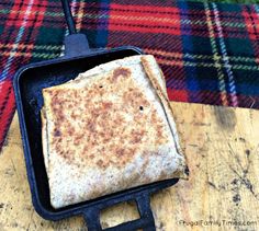 a pancake sitting on top of a wooden cutting board next to a plaid blanket