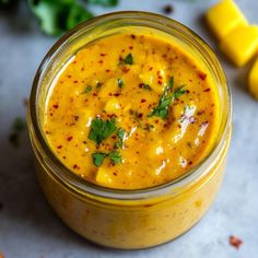 a glass jar filled with yellow sauce and garnished with parsley