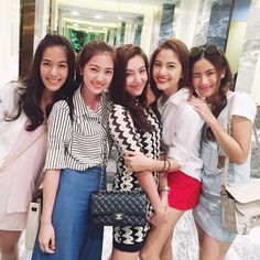 four young women posing for the camera in front of a hotel lobby door with their arms around each other