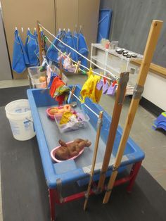 an infant's play table is set up with clothes and toys on the line