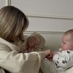 a woman holding a baby in her lap and looking at it's mother on the other side