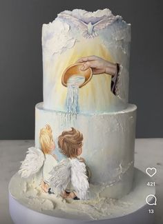 a three tiered cake decorated with angels and a hand holding a pie on top