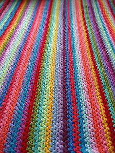 a multicolored crocheted blanket is laying on the floor