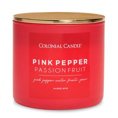 pink pepper passionfruit candle in a red glass jar with gold lid on white background