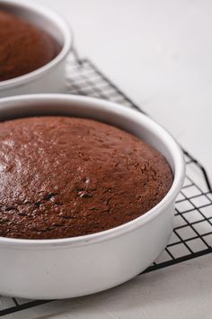 two cake pans sitting on top of a cooling rack filled with brownie batter