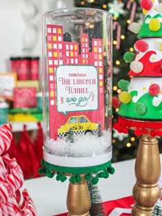 there is a glass jar with candy in it on top of a stand next to a christmas tree