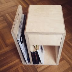 a small wooden table with magazines in it on the floor next to a hard wood floor