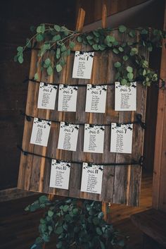 the seating plan is displayed on a wooden board with greenery and black string lights