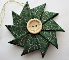 a green star ornament with a wooden button on it's center and the words merry christmas