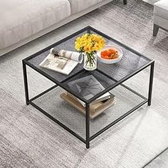 a glass coffee table with magazines and flowers on it