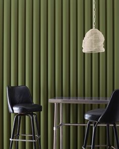 two chairs and a table in front of a green wall with vertical blindes on it