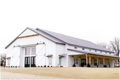 a large white barn with black doors and windows