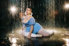 a woman is sitting on the ground in the rain