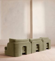 a green couch sitting on top of a hard wood floor next to a white wall