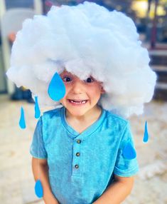 a young boy wearing a blue shirt and a white cloud hat with rain drops on it