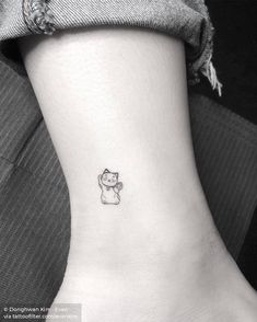 a small cat tattoo on the ankle is shown in black and white, with a tiny kitten