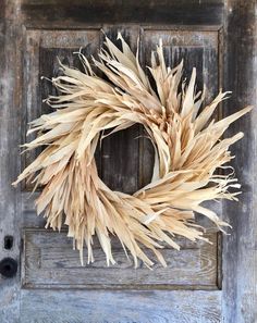 a dried wreath is hanging on the front door with an old wooden frame behind it