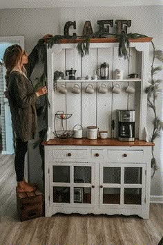 a woman standing in front of a white hutch