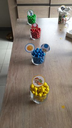 three bowls filled with candy sitting on top of a wooden table