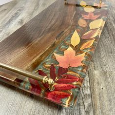 a wooden table topped with an umbrella covered in fall colored leaf designs on top of it