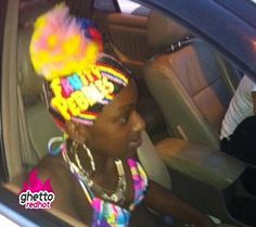 a woman sitting in the back seat of a car wearing a colorful head wrap and earrings