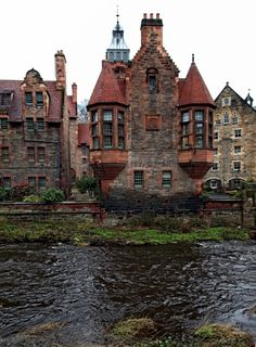 an old brick building sitting next to a river