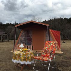 a tent set up in the middle of a field with a table and chairs around it