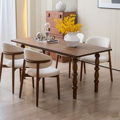 a dining room table with four chairs and a vase filled with yellow flowers on it