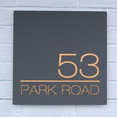 a sign that reads 53 park road on the side of a white brick building with gold lettering