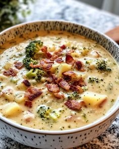 a bowl of soup with bacon and broccoli in it