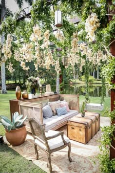 an outdoor living area with lots of furniture and flowers on the trees in the background