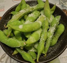 sugar snap peas in a black bowl with powdered sugar on the top and bottom