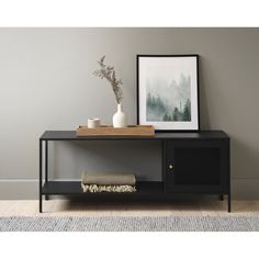 a black console table with a white vase on top and a framed photograph next to it