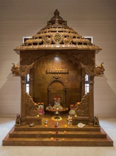 an elaborate wooden shrine with statues on the floor and decorations all around it in front of a wall