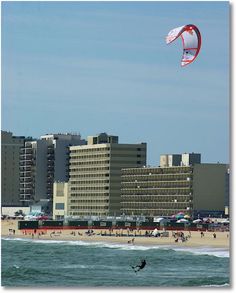 a person para sailing in the ocean next to a beach with hotels and buildings behind them